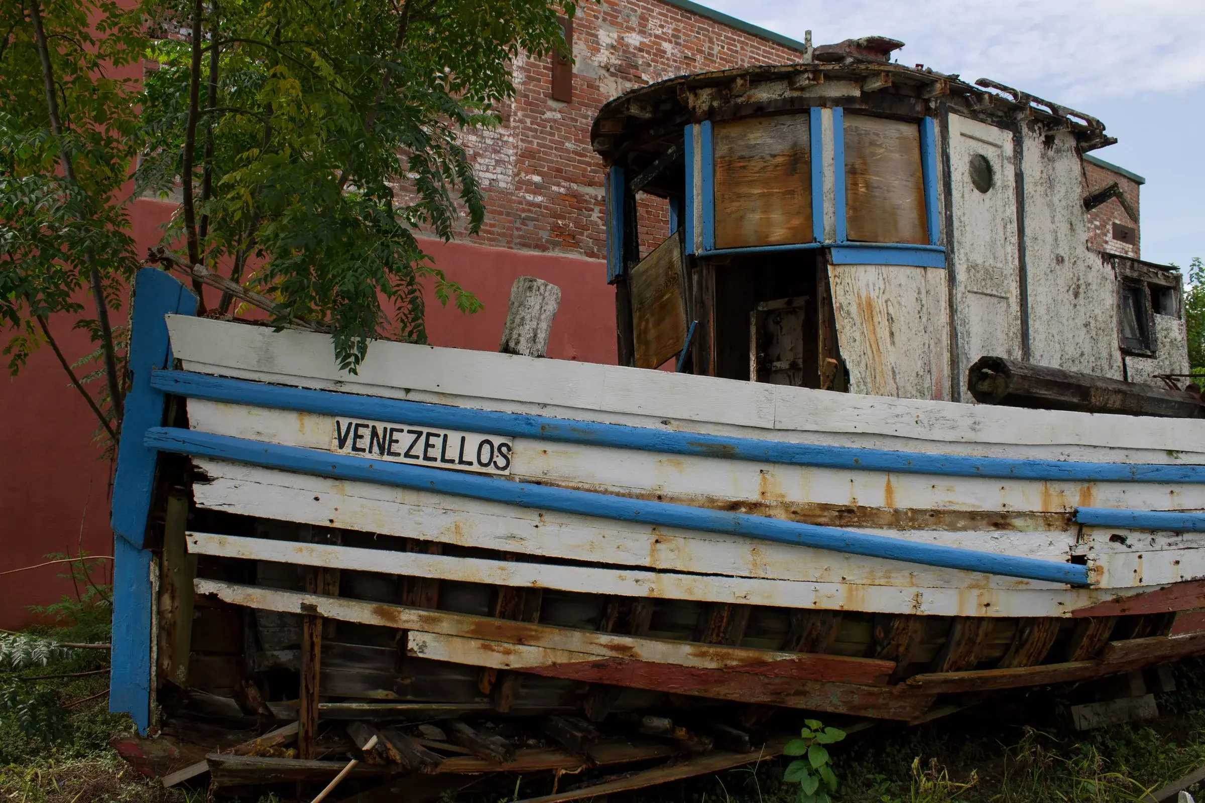 The wooden fishing boat Venezellos laid up on blocks against a brick wall on Avenue E in Apalachicola.