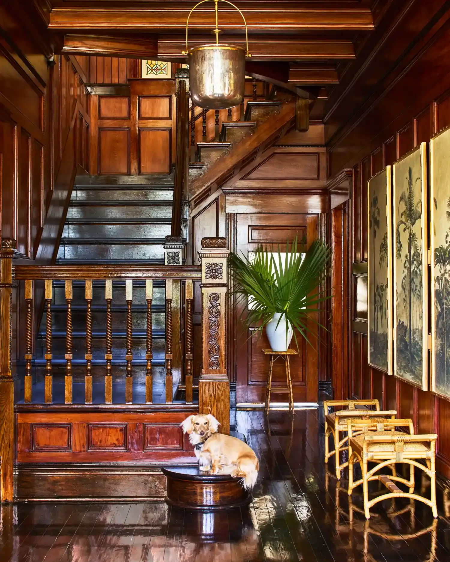 The stair hall: cypress and heart-pine paneling, coffered ceiling, carved corbels and turned balusters, all in a gloss finish.